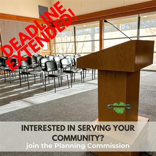 A picture of an empty Council Chamber with a podium and black chairs to sit in.