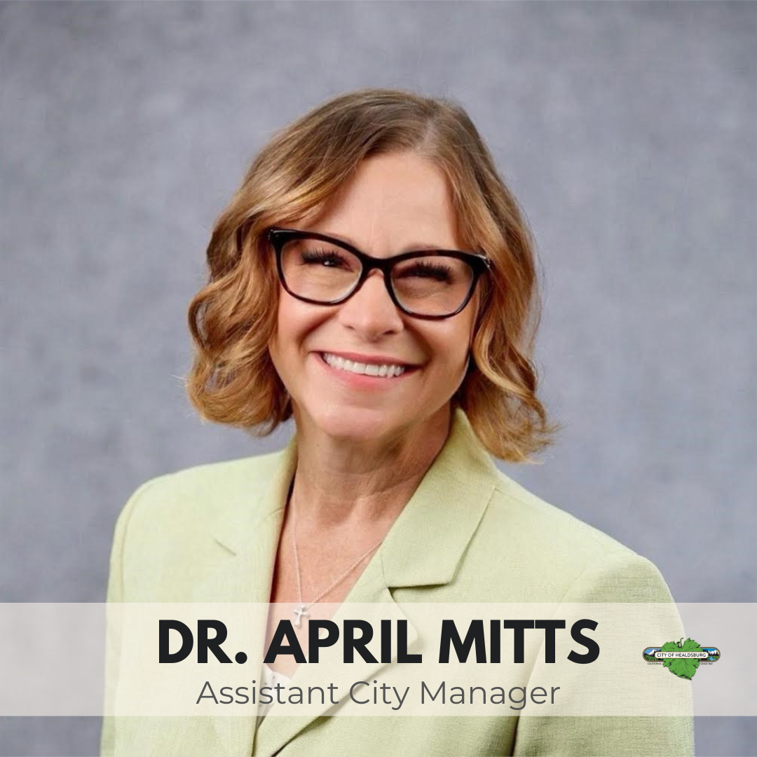 a picture of April Mitts. She is wearing a light green suit jacket with black glasses